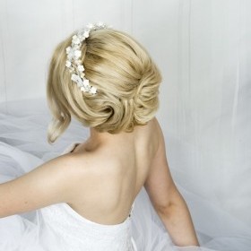 Свадебная прическа из коротких волос, удлиненная каре. Прическа воздушная и объемная, волосы около лица спадают прядями на левую сторону другая часть подколота на висок.
